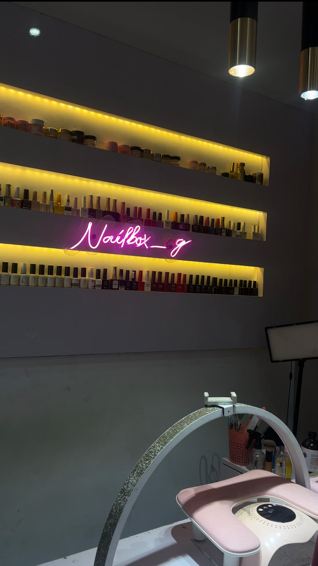 Inside the Nailboxng Beauty Studio with neon sign and polish wall